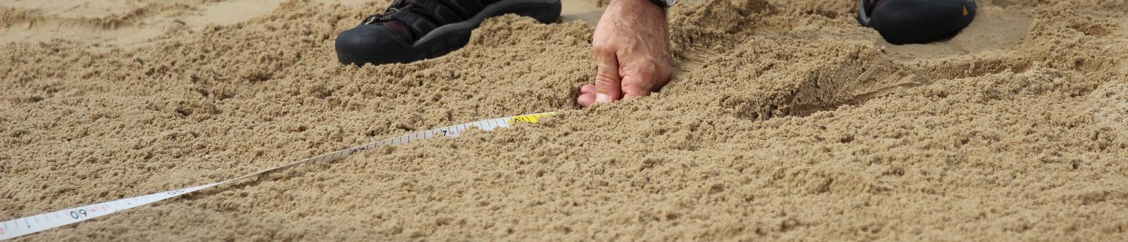 Messen: Zu sehen ist ein Maßband im Einsatz beim Weitsprung im Sand